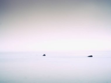 Kayalık deniz kıyısında pembe günbatımında. Yumuşak su seviyesi ve rüya gibi etkisi