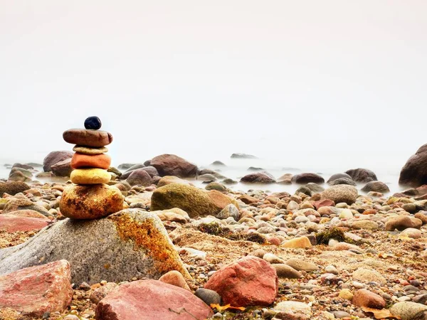 Kiegyensúlyozott kő piramis, a tenger partján, a hullámok a háttérben. Színes lapos kövekkel — Stock Fotó