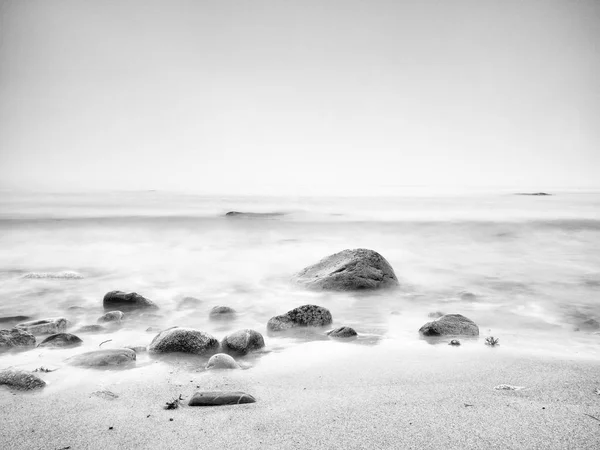 Romántico atardecer en el horizonte, reflejándose en la suave costa pedregosa — Foto de Stock