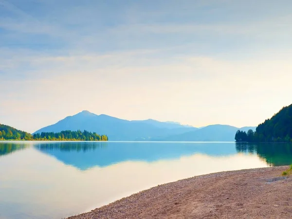 山の湖でロマンチックな夕日。石のビーチと暗い山中水ミラー. — ストック写真