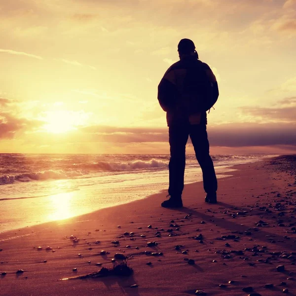 Man at evening sea. Hiker with backpack with hands in pocket along beach. — Stock Photo, Image