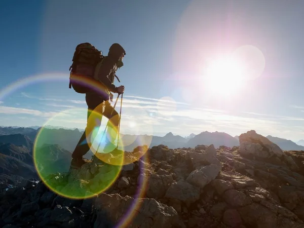 Lens flare defect.  Silhouette of man with hodd, backpack and poles in hand. Man walk — Stock Photo, Image