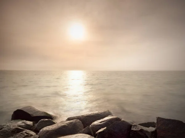 Grandes rocas húmedas en la costa en el mar ondulado suave. Costa pedregosa desafía a las olas — Foto de Stock