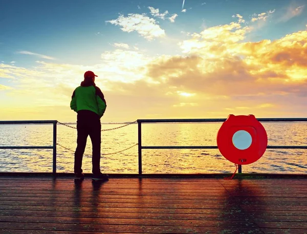 朝の地平線に海を見ているとほくろの手すりに立つ男 — ストック写真