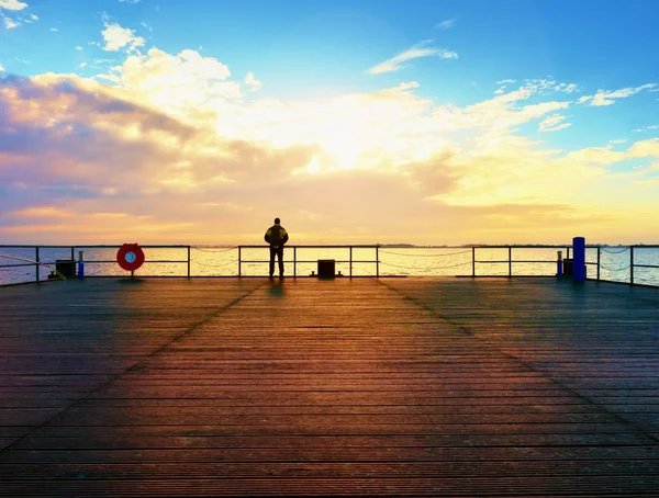 Mann wandert auf Maulwurf auf See. Tourist am Kai blickt über das Meer bis zum Horizont — Stockfoto