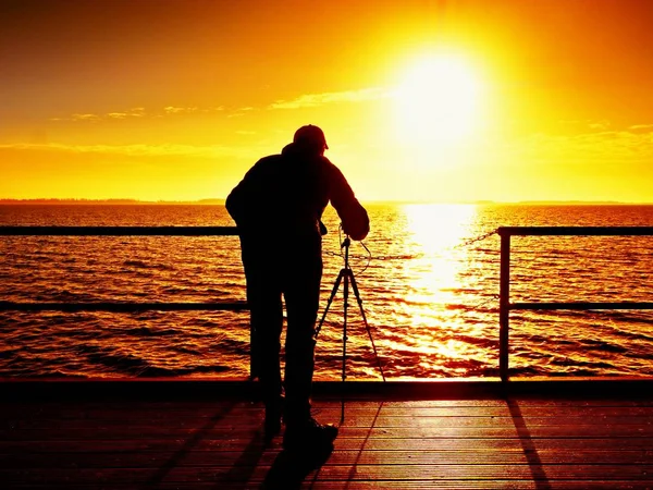 Photographer takes photos with mirror camera and tripod at end of pier board. — Stock Photo, Image