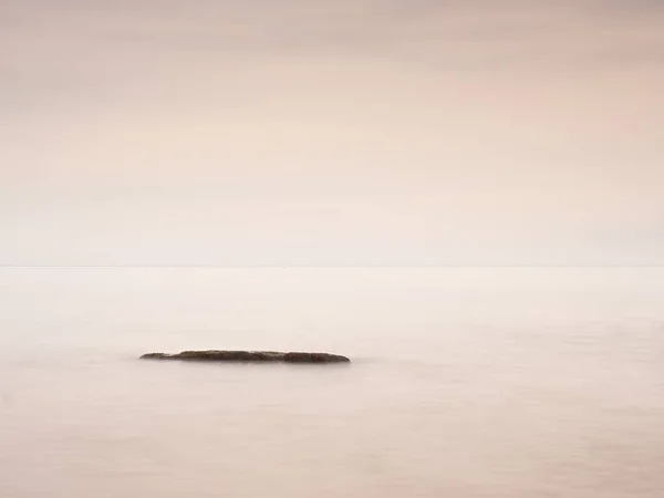 Mañana romántica en el mar. Grandes rocas que sobresalen del suave mar ondulado. Horizonte rosado con los primeros rayos de sol calientes. Efecto estilo Vintage — Foto de Stock