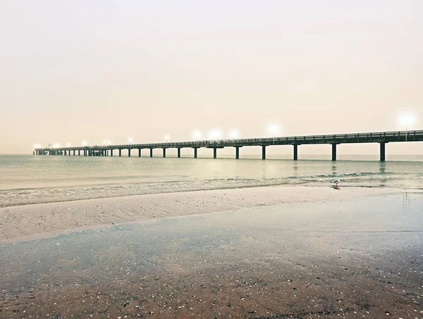 Höstens dimmiga morgon på träpiren ovanför havet. Depression, mörk atmosfär. Östersjön. — Stockfoto