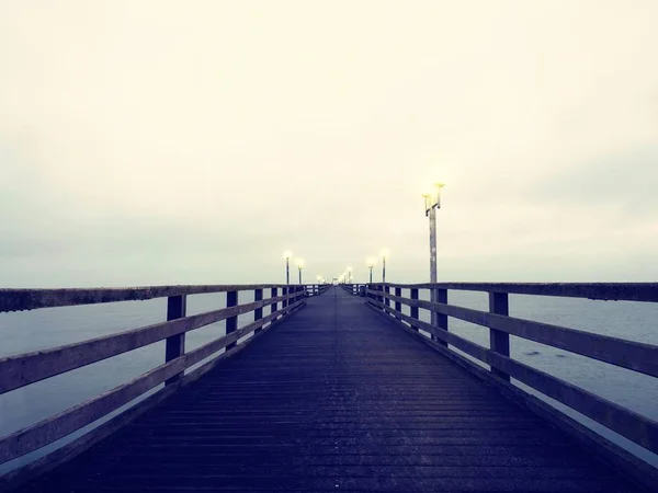 Deniz üstünde ahşap iskele sonbahar karanlık buğu. Depresyon, karanlık atmosfer. — Stok fotoğraf