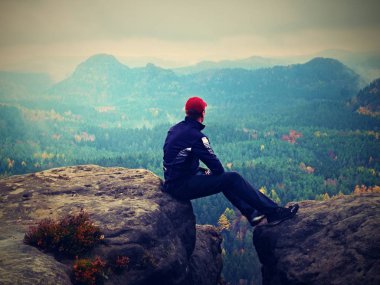 Siyahlı adam kırık kayalık imparatorluklar üzerinde oturmak. Melankoli sisli gün