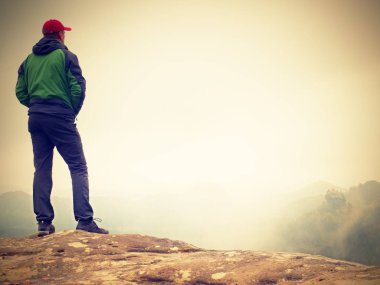 Siyah genç adam oturup Cliff'in kenar ve puslu Vadisi'ne bakıyor