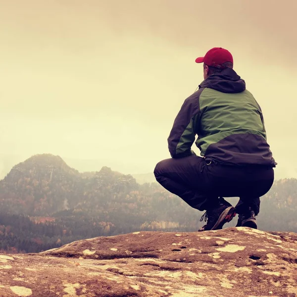Mladý muž v černém sedět na okraji útesu a chtějí mlhavé údolí — Stock fotografie