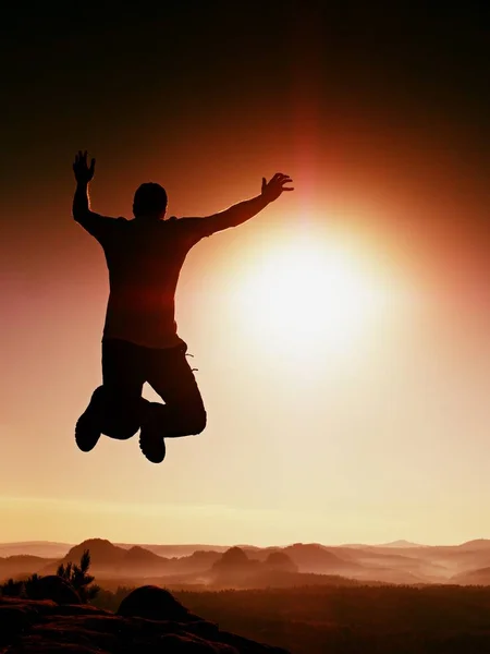 Saltando hombre. Joven loco está saltando en el cielo rojo background.Silhouette de hombre saltando — Foto de Stock