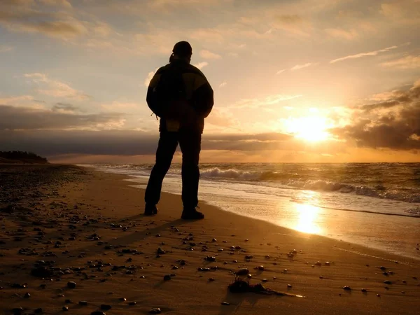 Man at evening sea. Hiker with backpack with hands in pocket along beach. — Stock Photo, Image