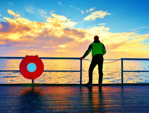 Einsamer Mann auf Pier und Blick über Geländer ins Wasser. Sonniger Himmel, glatter Wasserstand — Stockfoto