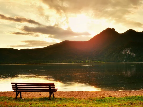 Empty bench at spring mountain lake. The coast with mountains at horizo — Stock Photo, Image