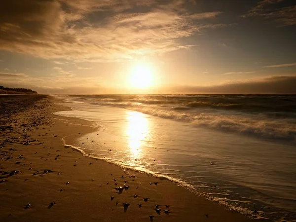 Piedras y senderos de agua en arena de playa. Rastros en la playa por mar suave — Foto de Stock