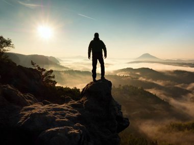 Cliff üzerinde yüksek ayakta adam. Uzun yürüyüşe çıkan kimse kayalık tepe kadar tırmandı ve manzarasının tadını çıkarın