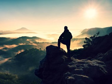 Cliff üzerinde yüksek ayakta adam. Uzun yürüyüşe çıkan kimse kayalık tepe kadar tırmandı ve manzarasının tadını çıkarın