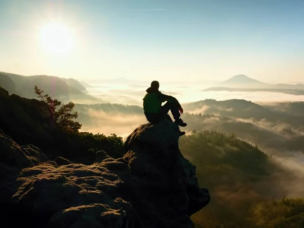 Der Mann sitzt auf einem Felsen. Aussichtspunkt mit Heidekraut und Zweigen — Stockfoto