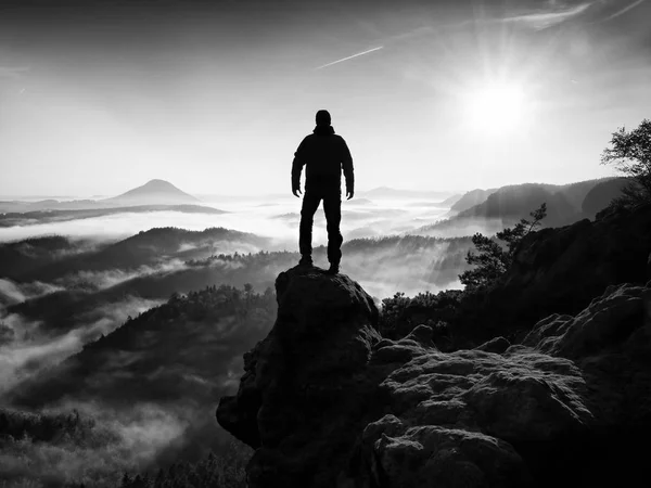 Jesienny mgliste rano w przyrodzie. Turysta w czarny stojak na szczyt w skale — Zdjęcie stockowe