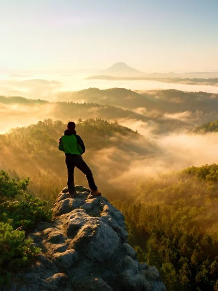 Autumnal  misty morning in nature. Hiker in black stand on peak in rock — Stock Photo, Image