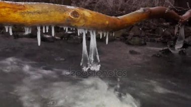 Soğuk su kış dağ nehir üzerinde asılı shinning buz sarkıtları detayını. Köpüklü akış yukarıda ışıltılı buz sarkıtları. Buz örtüsünün ve küçük gevreği toz kar düşmüş gövdeleri