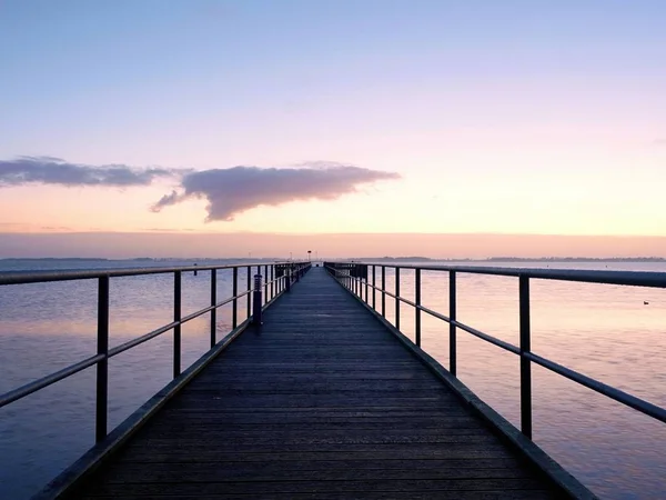 Long wooden pier on the Baltic coast during autumn morning. Cold weather