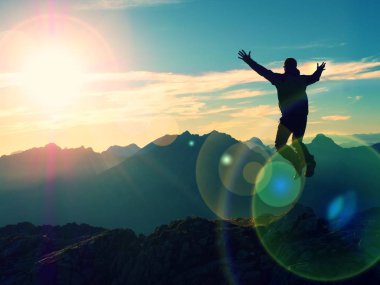 Lens flare etkisi. Yay açık daireler. Dağın zirvesinde atlama deli uzun yürüyüşe çıkan kimse. 