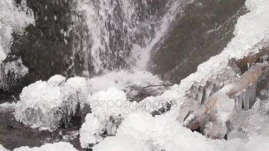 Iciciles şelale feryat. Karlı ve buzlu taşlar ve kayalar düşmüş soğuk su damlaları ile. Düşmüş Icicle feryat şelale, taşlı ve karlı akışı banka. Yakın odak.