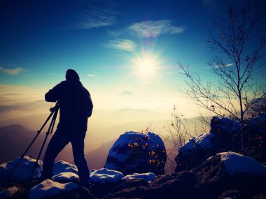 Güneşli erken kış sabahı. Fotoğrafçı hazırlanıyor fotoğraf makinesi tripod üzerinde. 