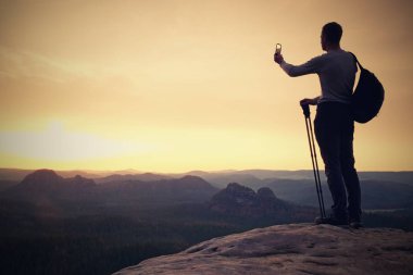 Uzun boylu backpacker telefonu el ile. Bahar daybreak dağlarda.