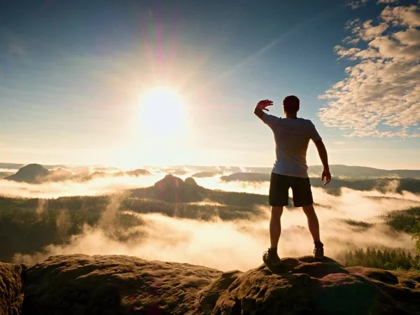 Fiatal sportoló shadowing szemét a fényes nap, hegy csúcs — Stock Fotó