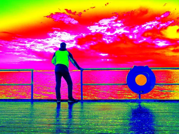 Infrarot-Foto. Mann steht am Geländer auf Maulwurf und blickt aufs Meer — Stockfoto