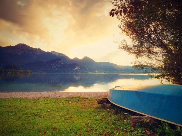 Upside down fishing paddle boat on bank of Alps lake. Smooth levelof autumnal lake. — Stock Photo, Image