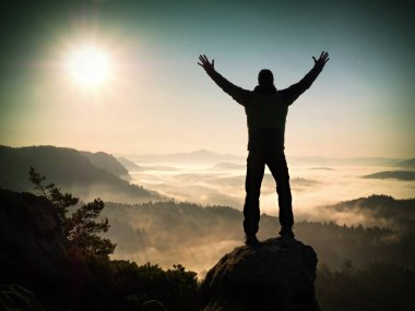 Adam uçurumun üzerinde tırmanma yüksek siluet. Zirveye kadar tırmandı hiker zevk görünümü.