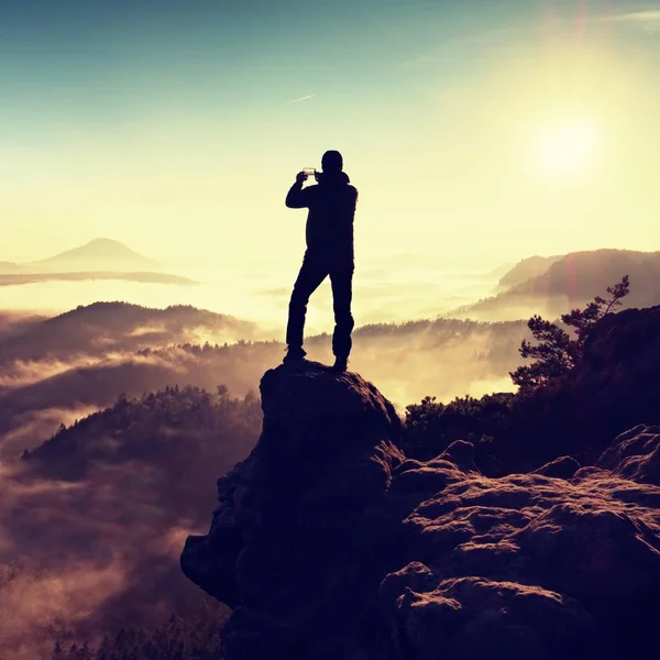 Турист фотографируется со смартфоном на вершине холмистой местности. Осенние туманные холмы — стоковое фото