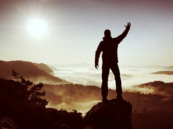 Un hombre feliz con un gesto de brazos levantados triunfa sobre un acantilado expuesto. Satisfacer excursionista — Foto de Stock