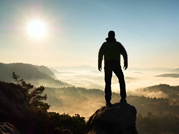 Autumnal  misty morning in nature. Hiker in black stand on peak in rock — Stock Photo, Image