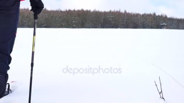 Kar ayakkabılarını walk ın under karlı olan adam. Uzun yürüyüşe çıkan kimse kırmızı kış ceket ve siyah pantolon toz karda snowshoeing trekking. Bulutlu kış günü, nazik Rüzgar küçük kar pul getiriyor.. 