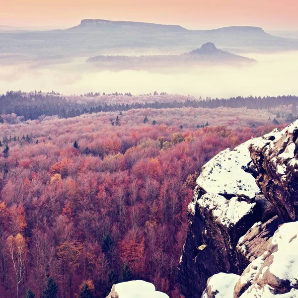 La primera cubierta de nieve en polvo en rocas de arenisca sobre el valle. Niebla pesada —  Fotos de Stock