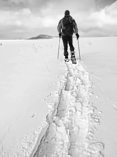 Caminante con mochila raquetas de nieve en deriva profunda. Hombre con paseo en la colina . —  Fotos de Stock