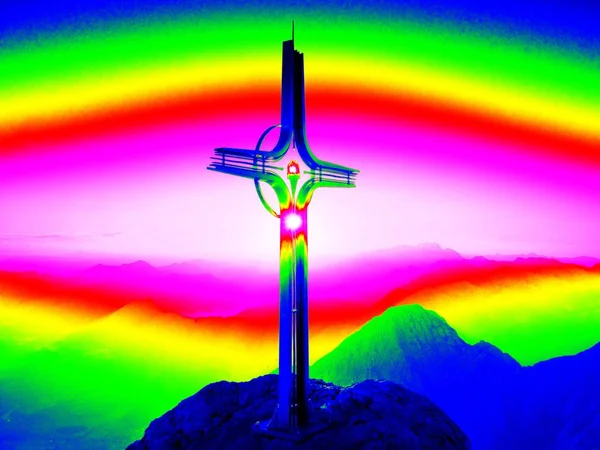 Infrared  photo. Steel crucifix at mountain peak in Alps.