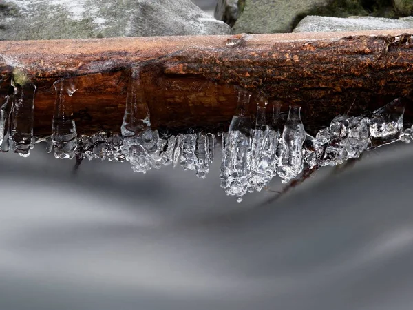 Isiga grenar ovanför kylning stream. Reflektioner i istappar — Stockfoto