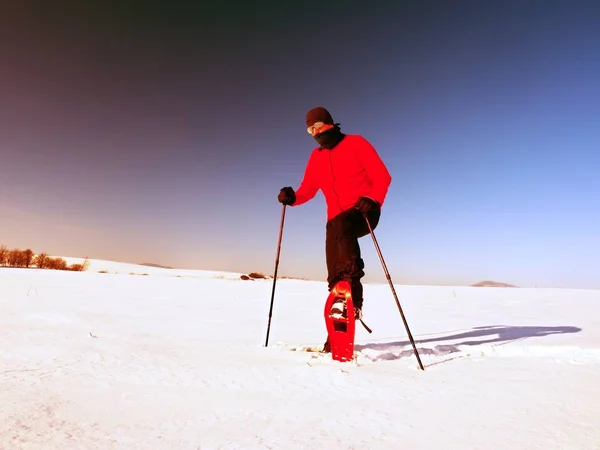 Mann putzt Schneeschuh. Wintertourist mit Schneeschuhen im Schnee — Stockfoto