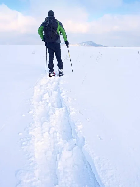 Caminhante com mochila snowshoeing em deriva profunda. Homem com caminhada na colina . — Fotografia de Stock