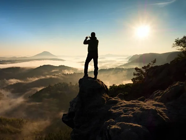 Man står hög på klippa. Hiker klättrade upp till rocky topp och njut av utsikten — Stockfoto