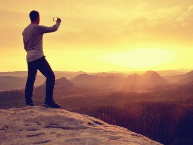Adam dağlarda trekking Polonyalılar ile akşam bir yürüyüş için. Siyah sporcu elleri ceplerinde stand rock empires park ve adam silüeti güneş puslu ve sisli sabah Vadisi'ne üzerinden izlerken tepe üzerinde.