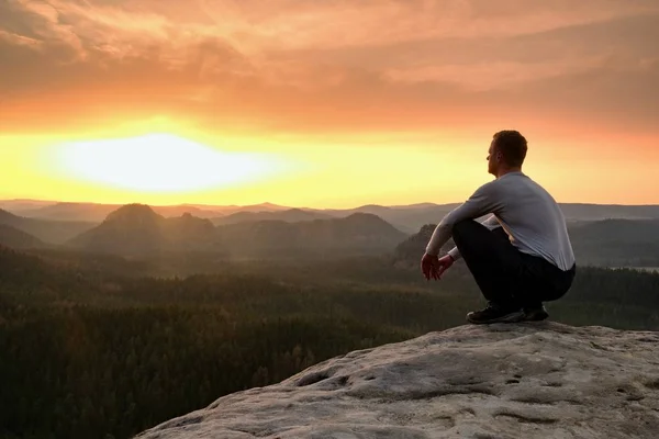 검은 앉아 혼자 바위 정상에 있는 등산객. 산에서 멋진 새벽 무거운 안개 깊은 계곡에. 남자는 바위에 앉아. — 스톡 사진