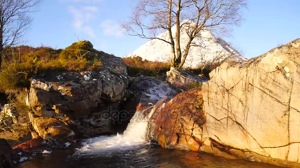 Bekende waterval op de rivier Coupall bij delta rivier Etive. In achtergrond besneeuwde kegel van berg Stob Dearg 1021 meter hoog. Higland in Schotland een prachtige zonnige winterdag. Droog gras. — Stockvideo